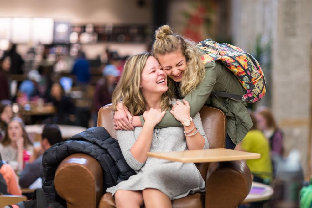 Two friends hug in the A. W. Clausen Center near Starbucks.